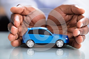 Businessman`s Hand Protecting Blue Toy Car