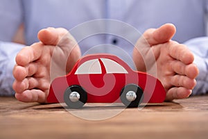 Businessman`s Hand Protecting Red Toy Car
