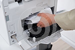 Businessman`s Hand Removing Paper Stuck In Printer