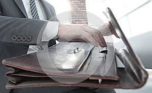 Businessman`s hand with suitecase in a modern office