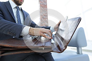 Businessman`s hand with suitecase in a modern office