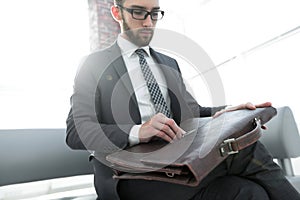 Businessman`s hand with suitecase in a modern office