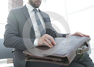 Businessman`s hand with suitecase in a modern office