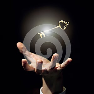 A businessman`s hand is trying to grab a golden key a symbol of good luck and wealth