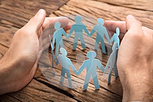 Businessman`s Hands Covering Paper Team On Table