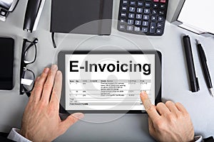 Businessman`s Hands Going Through E-Invoicing On Digital Tablet photo