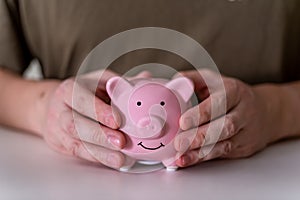 The businessman`s hands hold a pink piggy bank