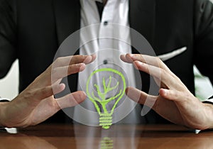 Businessman`s hands over a green leaf lightbulb-eco friendly concept