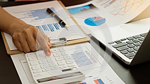 Businessman`s hands pressing a calculator, calculating, analyzing, graphing, charting, accounting worker working on a laptop. A ba