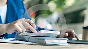 Businessman`s hands pressing a calculator, calculating, analyzing, graphing, charting, accounting worker working on a laptop. A ba