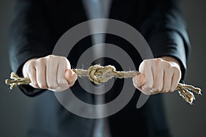 The businessman`s hands tighten the rope knot against background of suit in blur