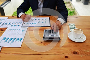 Businessman's hands using calculator and Financial data analyzing on wooden desk at the office