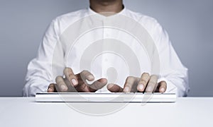 Businessman`s hands in white shirt typing on modern keyboard computer.