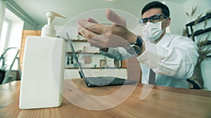 Businessman is sanitizing hands while working on a laptop from home. Man work at home in quarantine during covid-19