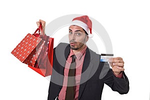 Businessman in Santa Claus Christmas hat holding sopping bags and credit card in worried and stress