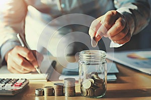 businessman saving money concept. hand holding coins putting in