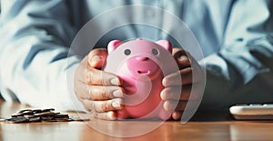 businessman saving money concept. hand holding to protection piggy bank