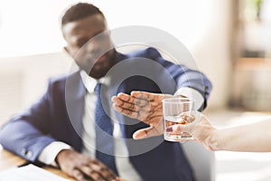 Businessman saying no to glass of whiskey offered by colleague