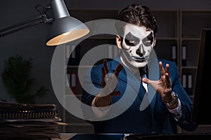 The businessman with scary face mask working late in office