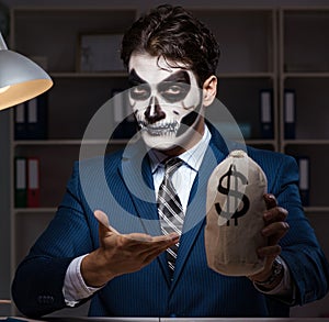 Businessman with scary face mask working late in office