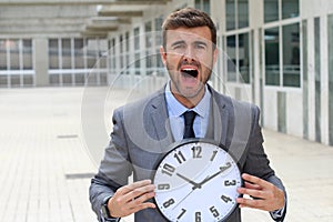 Businessman screaming while holding a big clock