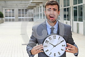 Businessman screaming while holding a big clock