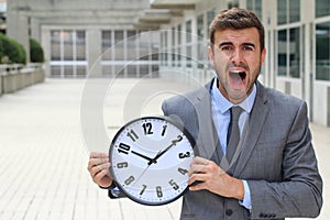 Businessman screaming while holding a big clock