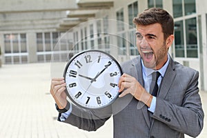 Businessman screaming while holding a big clock