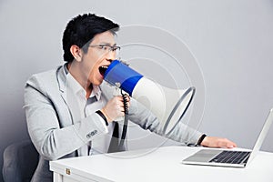 Businessman screaming in megaphone on laptop