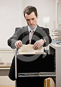 Businessman searches through file drawer