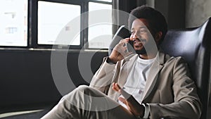 A businessman is seated engaged in a pleasant conversation on his smartphone