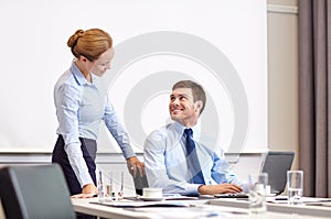 Businessman and secretary with laptop in office