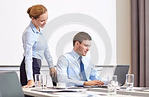 Businessman and secretary with laptop in office