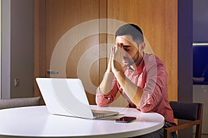 Businessman seet front at his pc and prayingr