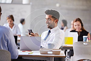 Businessman Sending Text Message In Mobile Phone In Office