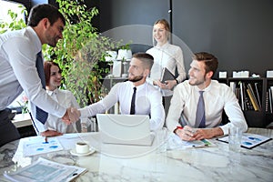 Businessman shaking hands to seal a deal with his partner and colleagues in office