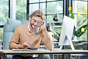 Businessman in shirt doing paperwork, man working with documents, contracts and bills sitting at table using laptop at