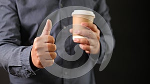 Businessman show thumb and holding favorite hot coffee cup. Excellent review drink business concept