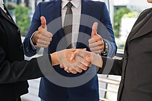 Businessman show thumb up and businesswoman shaking hands for demonstrating their agreement to sign agreement between their firms