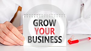 Businessman showing a card with text GROW YOUR BUSINESS, business and positive concept