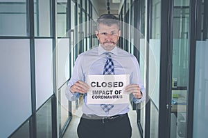 Businessman showing closed impact of coronavirus text