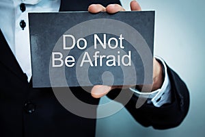 Businessman showing Do Not Be Afraid word on cardboard.