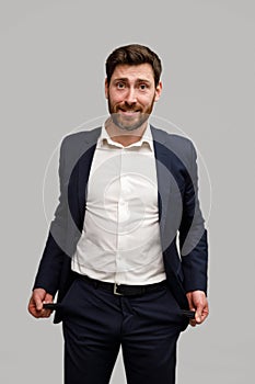 Businessman showing his empty pockets standing on grey studio background