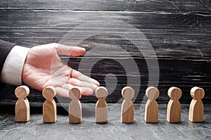 Businessman showing his hand to the wooden figures of people, workers. Hiring workers, human resources, headhunters.