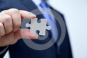 Businessman showing a jigsaw puzzle piece. Business and teamwork concept