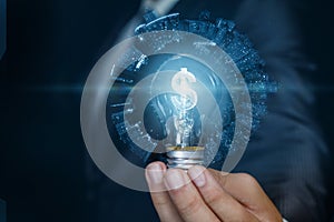 Businessman showing light bulb with burning dollar hologram inside on blue background