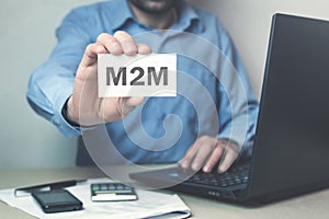 Businessman showing M2M word on business card.