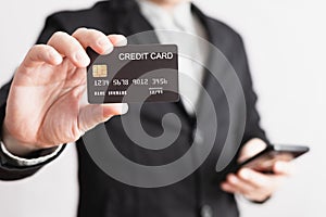 businessman showing a mock-up credit card for shopping to make payment and smartphone.half body. Concept for banner, purchase,