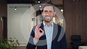Businessman showing ok gesture while expressing positive emotion at office