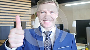 Businessman showing OK sign with his thumb up. Selective focus on face.